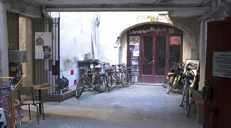 Entrée de la librairie du muguet à Bordeaux, où le festival Ladyi*fest a eu lieu. L'entrée est une grande porte ronde au fond d'une petite place où sont garés de nombreux vélos.